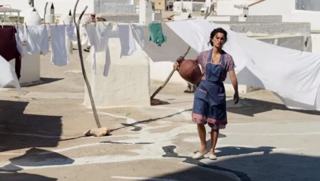 Mujer con un delantal azul azotea soleada con ropa blanca tendida al fondo Cine Español