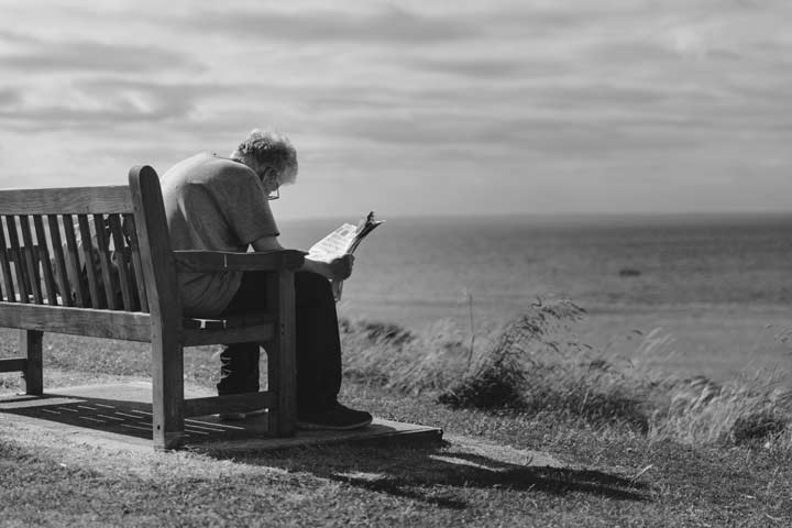 Señora mayor anciana leyendo periodico frente al mar